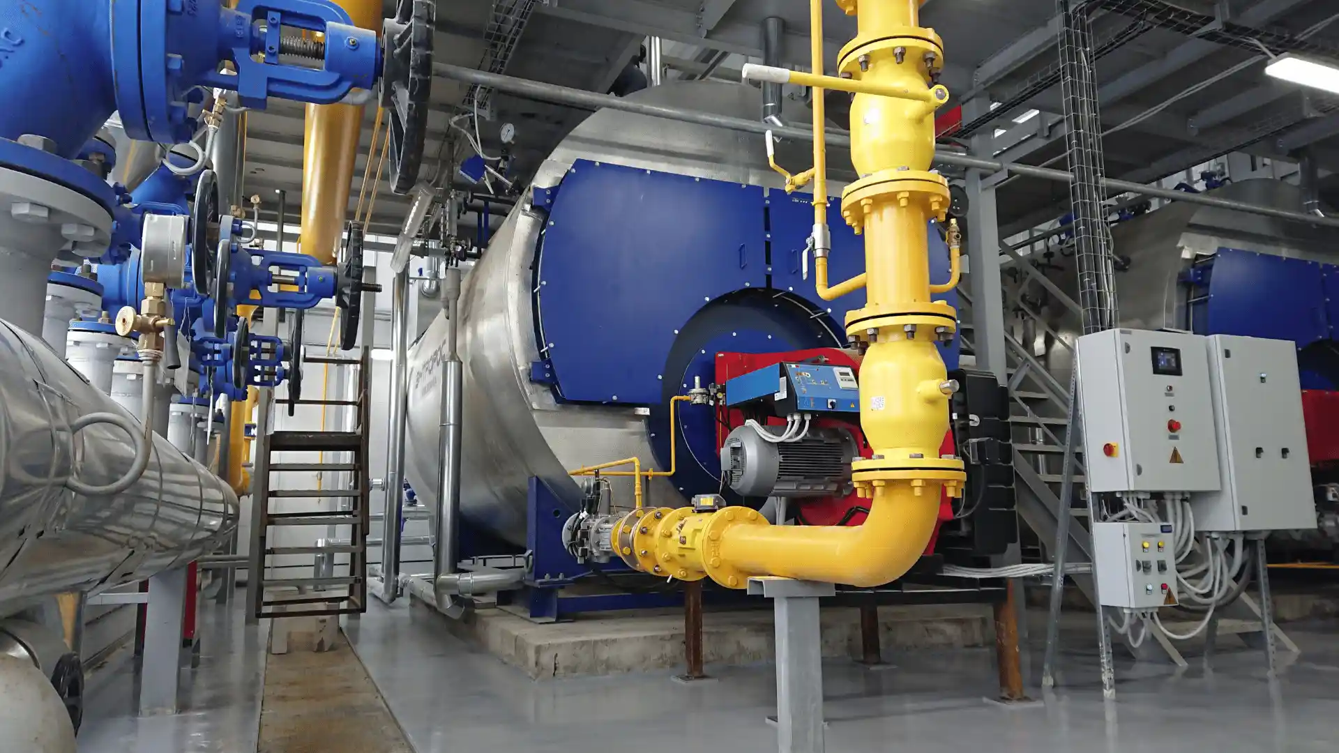 Instalasi boiler uap industri dengan jaringan pipa, burner, dan panel kontrol.